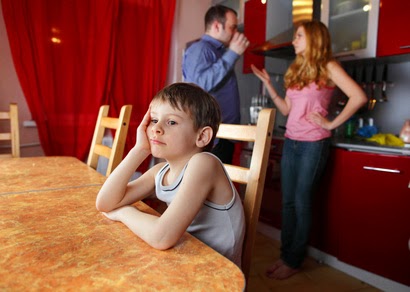 Niño en la mesa de la cocina mientras sus padres discuten