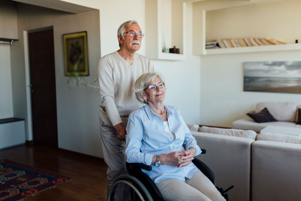 Hombre mayor ayudando a su mujer en silla de ruedas.