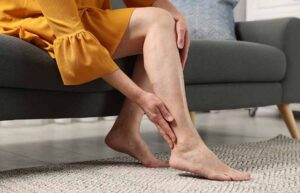 Mujer sentada en el sofá masajeándose la pierna