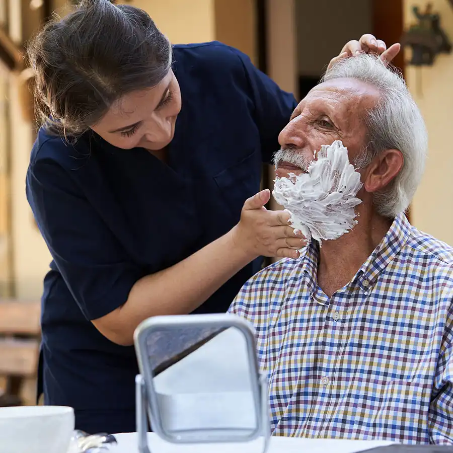Cuidadora afeitando un hombre mayor