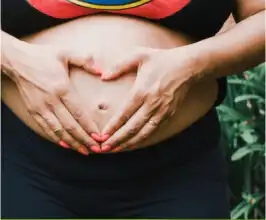 Mare fent un cor sobre la seva panxa